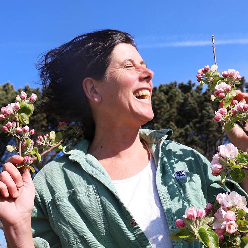 Hetty laughing in between apple blossom branches